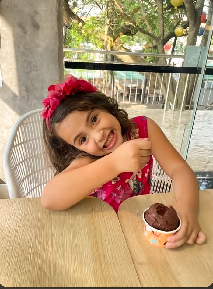 Cliente pequena sorrindo com seu potinho de gelato de chocolate